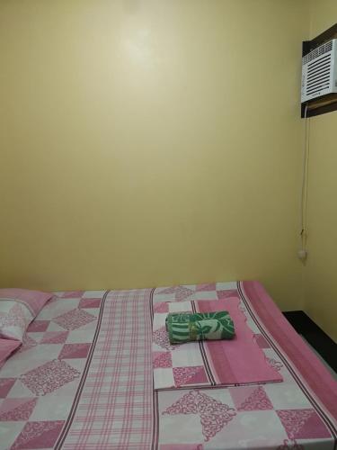 a bed with a pink and white quilt on it at Joyful Guest House in El Nido