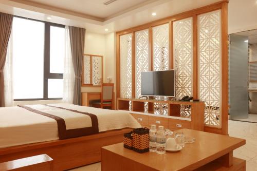 a bedroom with a bed and a tv and a table at Thanh Bình Gold Hotel in Sầm Sơn