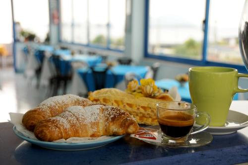a table with two plates of pastries and a cup of coffee at Hotel Villa Del Mare in Bacoli