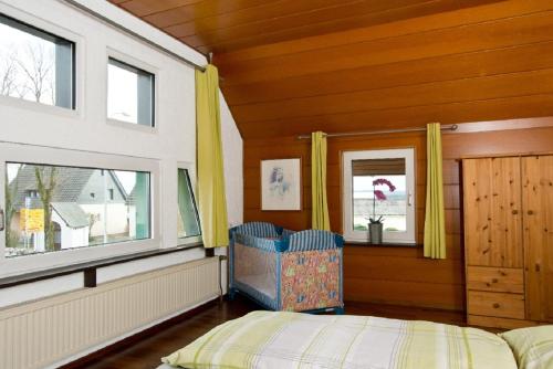 a bedroom with a bed and two windows at Ferienhaus im Grünen Eifel in Schleiden