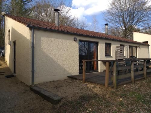 a small white house with a porch and a deck at Bungalows du Lac de Rabais in Virton