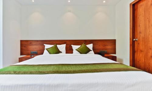 a bedroom with a large white bed with green pillows at Treebo Blu Orchid in Bengaluru