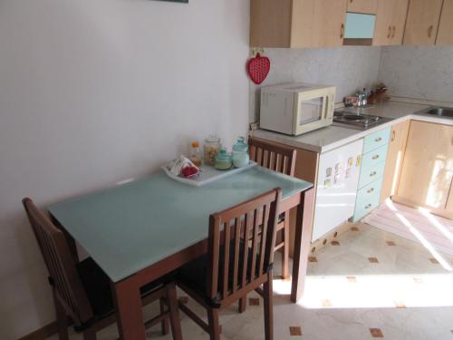 cocina con mesa, sillas y microondas en Zara Apartment, en Treviso