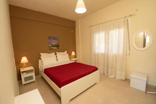 Un dormitorio con una cama grande con una manta roja. en Seaside Apartments-Angela, en Kalí Limenes