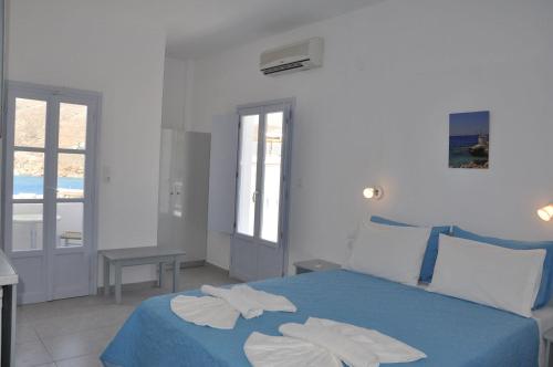 a bedroom with a blue bed with towels on it at Studios Akrogiali in Aegiali