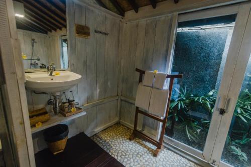 baño pequeño con lavabo y ventana en Green Taman Ubud by Prasi, en Ubud