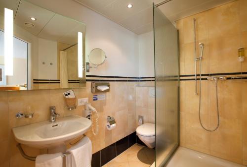 
a bathroom with a sink, toilet and shower at Engimatt City & Garden Hotel in Zurich
