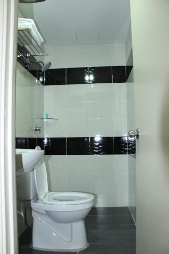 a bathroom with a white toilet and a black tile wall at Hotel Eastana Ipoh in Ipoh
