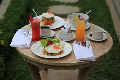 una mesa de madera con platos de comida y bebidas en Green Taman Ubud by Prasi, en Ubud