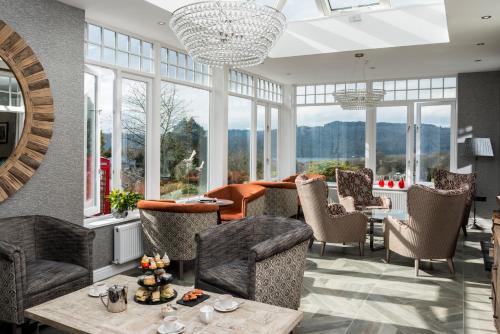 a living room with chairs and tables and windows at Windermere Hillthwaite Hotel in Windermere
