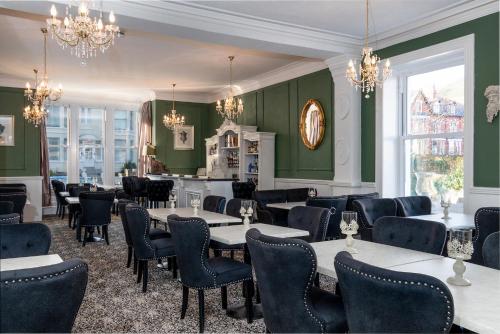 a restaurant with green walls and tables and chairs at Lansdowne House with Private Car Park in Llandudno