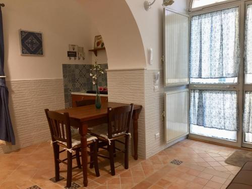 een keuken met een houten tafel en stoelen en ramen bij Trio D'Archi - La Maison de Cocò in Caltagirone