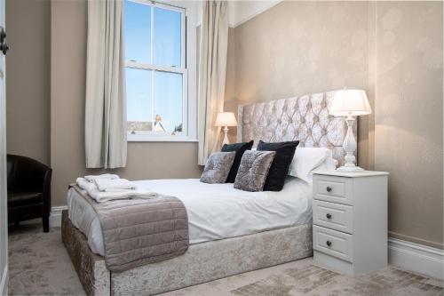 a bedroom with a white bed with a window and a chair at Lansdowne House with Private Car Park in Llandudno
