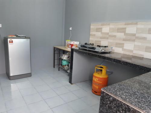a kitchen with a counter and a refrigerator at Anis Homestay Gua Musang in Gua Musang
