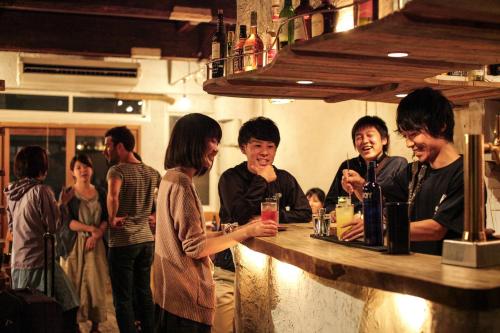 a group of people standing around a bar at Guesthouse toco in Tokyo