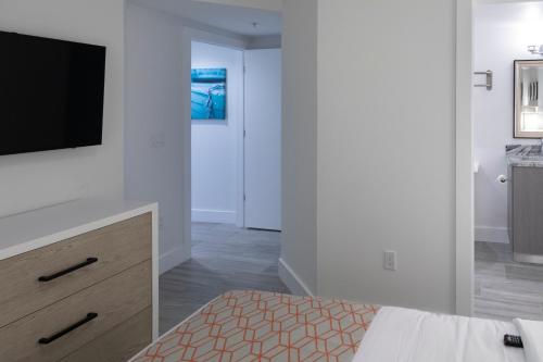 a bedroom with a tv on a wall and a bed at Provident Oceana Beachfront Suites in St Pete Beach