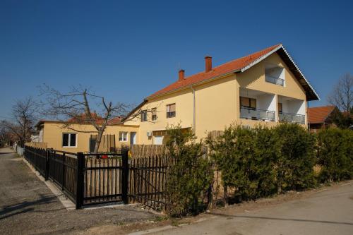 a yellow house with a fence in front of it at Apartments Kuca Aleksic in Niš