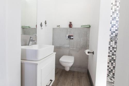 a white bathroom with a sink and a toilet at Sweetwater Guesthouse in Wellington