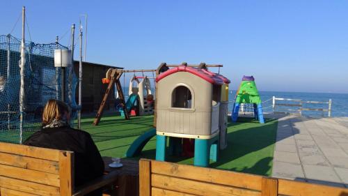 une femme assise sur un banc à côté d'une aire de jeux dans l'établissement La Magnolia, à Porto SantʼElpidio