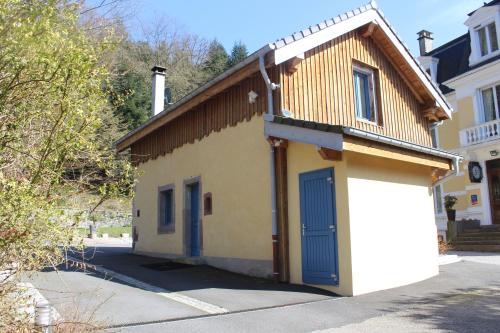 a small yellow building with a blue garage at le 18 bis in Vecoux