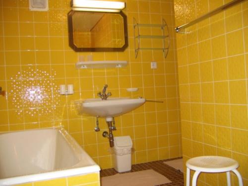 Baño amarillo con lavabo y bañera en Ferienwohnung Irene, en Tux