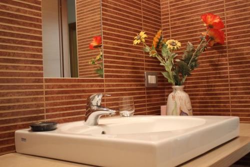 a bathroom sink with a vase of flowers and a mirror at B&B Casa Vanzetta in Ziano di Fiemme