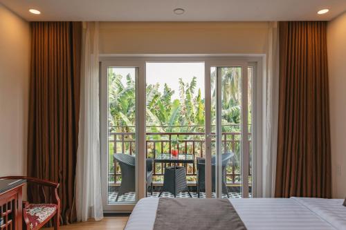 1 dormitorio con 1 cama y balcón con mesa en Nu Ni Homestay, en Hoi An