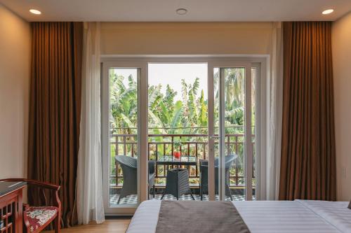 a bedroom with a bed and a balcony with a table at Nu Ni Homestay in Hoi An