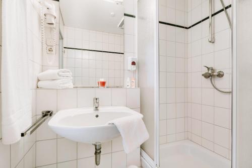 a white bathroom with a sink and a shower at Hotel Radau in Bad Harzburg