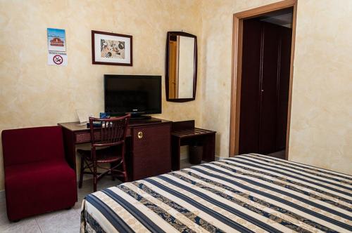 een slaapkamer met een bed, een bureau en een televisie bij B & B Appia Antica in Mesagne