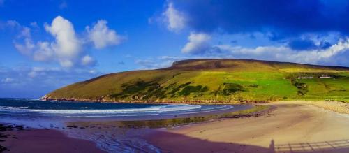 a green hill sitting on top of a beach at Cozy & Remote Hideaway Gintys Cottage in Ross Port