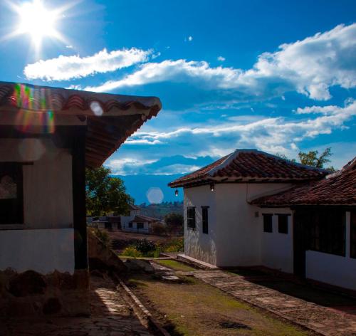 two white houses with the sun in the sky at Posada Campestre La Casona in Villa de Leyva