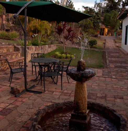 a fountain with chairs and a table with an umbrella at Posada Campestre La Casona in Villa de Leyva