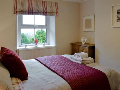 a bedroom with a bed with a window and towels on it at Middlegate Cottage in Hawes
