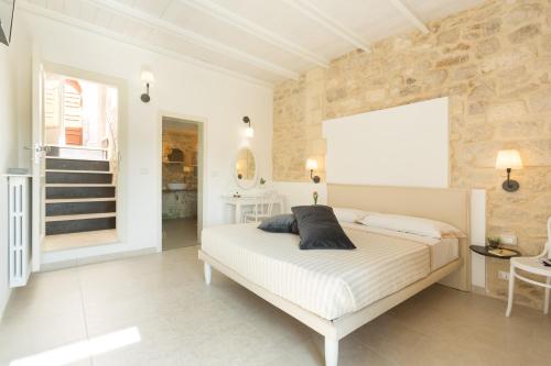 a bedroom with a white bed and a stone wall at Evoca in Ragusa