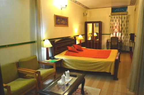 Hotel Vimal Heritage في جايبور: غرفة نوم بسرير وكرسي وطاولة