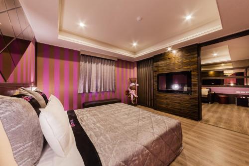 a bedroom with a bed and a flat screen tv at QK Motel in Taoyuan