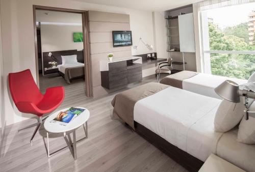 Inntu Hotel في ميديلين: غرفة فندقية بسريرين وكرسي احمر