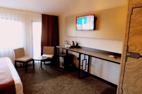 Habitación de hotel con escritorio y TV en la pared en Respiro Boutique Hotel, en Avcılar