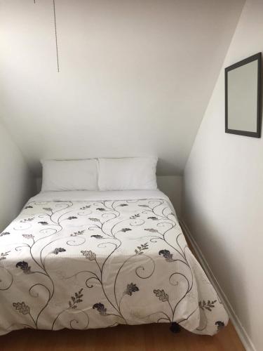 a bedroom with a bed with a flowered blanket at La petite maison sur la côte in Sainte-Anne-des-Monts