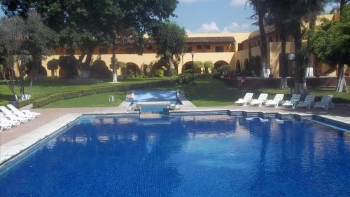 a large swimming pool with chairs and a building at Casa Cantarranas in Tehuacán