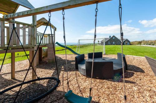 a swing set in a playground with a swing at Ocean View,Kinsale, Hosted by Exquisite holiday homes, sleeps 22 in Kinsale