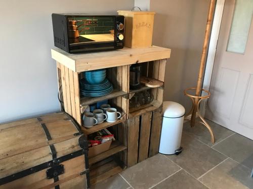 a microwave on a wooden stand with a tv on it at Fistral Court in Newquay