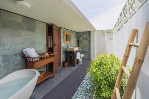 a bathroom with a tub and a toilet and a sink at Oceanfront Citakara Sari Villas in Candidasa