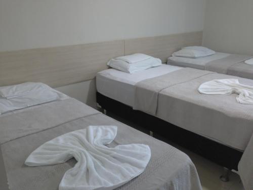 a room with three beds with white sheets on them at Hotel Litoral Fortaleza in Fortaleza