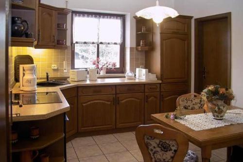 a kitchen with wooden cabinets and a table and a window at Ferienwohnungen "Johannesberg" in Fischbach