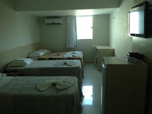 a room with three beds and a flat screen tv at Hotel Litoral Fortaleza in Fortaleza