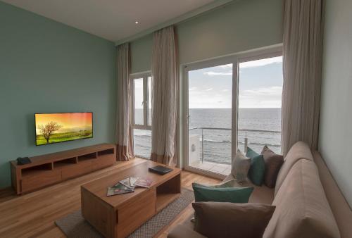 a living room with a couch and a large window at Ocean Edge Suites & Hotel Colombo in Colombo
