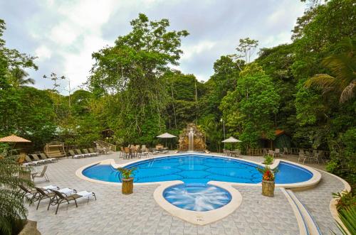 a swimming pool with chairs and a table at Evergreen Lodge in Tortuguero