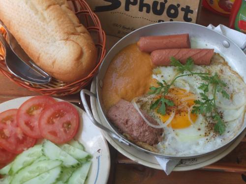 einen Teller Essen mit Wurst und Ei und ein Sandwich in der Unterkunft S Phuot Ban Me Homestay in Buon Ma Thuot